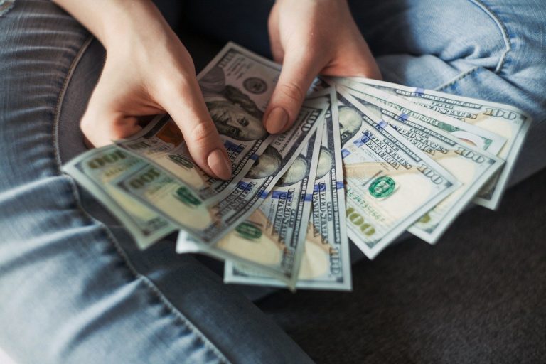 Gewerbefinanzierung & Privatkredite Eine Person hält mehrere 100-Dollar-Scheine in den Händen.